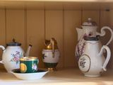 a shelf with a tea pot, tea cup, and other items on it