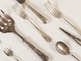 many forks and spoons laid out on a white surface