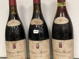 trois bouteilles de vin posées sur une étagère en verre, à côté d'une bouteille de vin