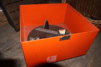 une boîte orange contenant un disque, posée sur un plancher en bois