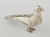 silver bird figurine with turquoise eyes sitting on a white surface