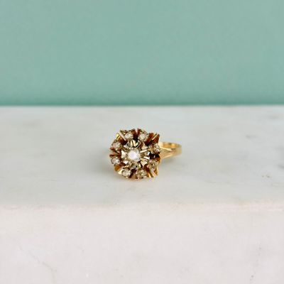 un gros plan d'une bague en or ornée d'une fleur, posée sur une table