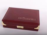 La boîte est rouge, ornée de motifs dorés, et porte un nom.