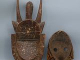 two wooden masks are sitting next to each other on a gray surface