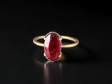 a gold ring with a red stone on a black surface