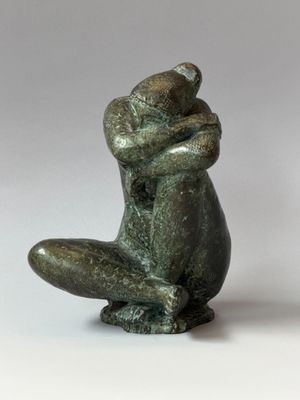 statue d'un homme assis sur ses genoux, les bras croisés