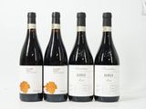 quatre bouteilles de vin sont alignées sur une surface blanche