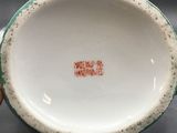 a white bowl with a green rim and a red inscription on it