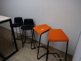 trois tabourets noirs et orange placés les uns à côté des autres sur un parquet
