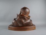 bronze bust of a man with a hat on a wooden base