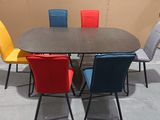 brightly colored chairs sit around a rectangular dining table in a room