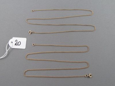 un ensemble de colliers en or et une étiquette posés sur une surface grise