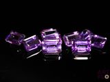 trois morceaux de verre violet reposent sur une surface noire