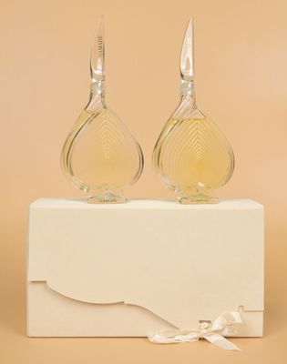 a pair of perfume bottles sitting on top of a white box