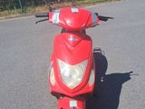 un scooter rouge garé sur un parking