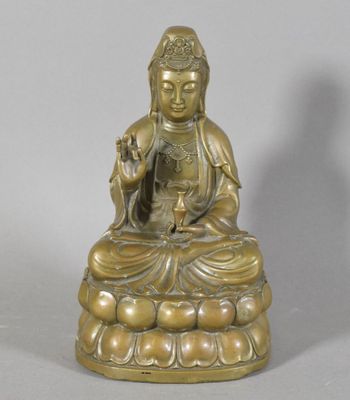 brass statue of a person sitting on a rock with a bird in his hand