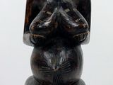 une statue en bois représentant une femme assise sur un tabouret