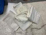 a pile of white clothing on the floor next to a blue suitcase