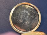 a close up of a pocket watch with a key on a table