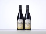 two bottles of red wine sitting on top of a table