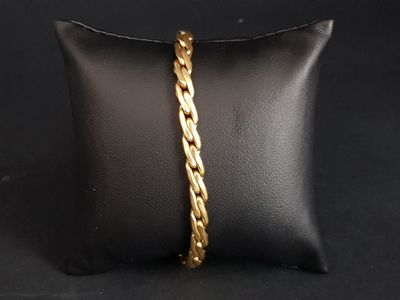 a gold plated bracelet with a braid design on a black pillow