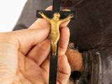 hand holding a cross with a statue of a man on it