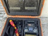 une mallette orange posée par terre, contenant des outils