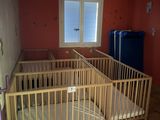 deux lits bébé dans une chambre avec une fenêtre et une poubelle