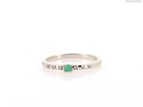 a close up of a white gold ring with a emerald and diamonds