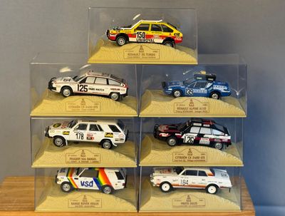 six modèles réduits de voitures différents, exposés dans une vitrine posée sur une table