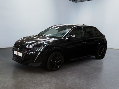 La voiture noire est garée dans une grande pièce aux murs blancs.