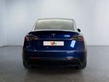 the back of a blue tesla vehicle parked in a white room