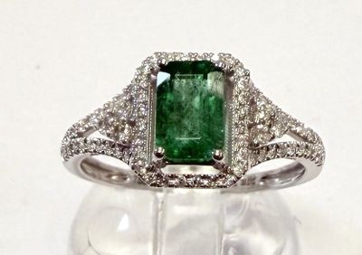 une photo d'une bague ornée d'une pierre verte entourée de diamants