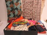 une valise noire remplie de vêtements et de cravates posée sur un lit