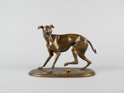 statue en bronze représentant un chien en train de courir, posée sur un socle sur lequel se trouve une balle