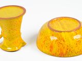 two yellow vases sitting next to each other on a white surface