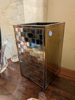 une poubelle argentée posée sur une table à côté d'un miroir
