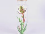 un vase contenant une fleur, posé sur une surface blanche