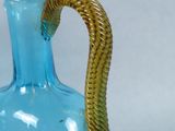 a blue glass vase with a gold handle on a table