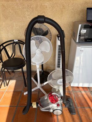 a vacuum and a fan on the floor next to a chair