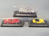 three die cast cars in plastic cases sitting on a table