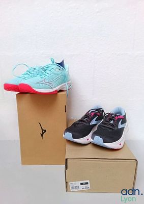 une paire de chaussures de course bleues et roses posée sur une boîte en carton