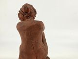 an image of a statue of a woman sitting on a white surface