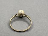 an image of a pearl and diamond ring on a gray surface