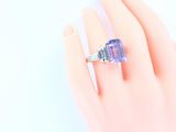 someone is holding a ring with a purple and blue stone