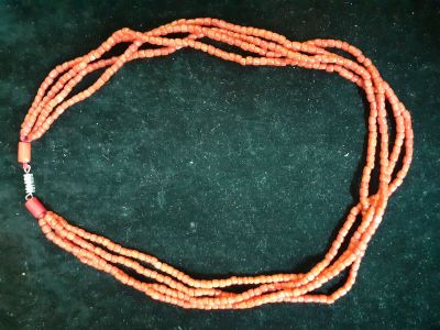 an image of a necklace made of orange beads on a black surface