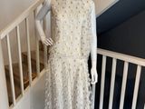 Le mannequin porte une robe blanche et un chapeau de paille.