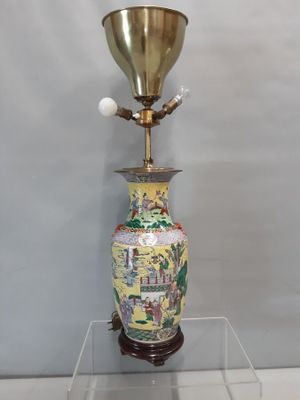 a vase that is sitting on a table with a lamp on top of it