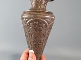 a person holding a metal vase in their hand