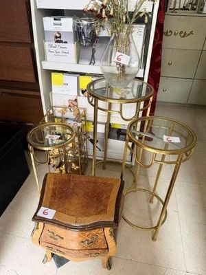 trois tables et une chaise dans un magasin, avec un vase de fleurs posé sur la table